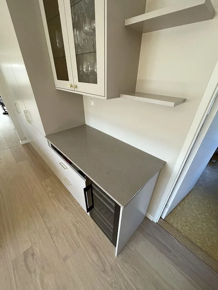 Köksbänkskiva i beige Silestone Coral Clay vid en vitrinkåpa med glasluckor i ett kök i Hässelby, fotograferad under montering.