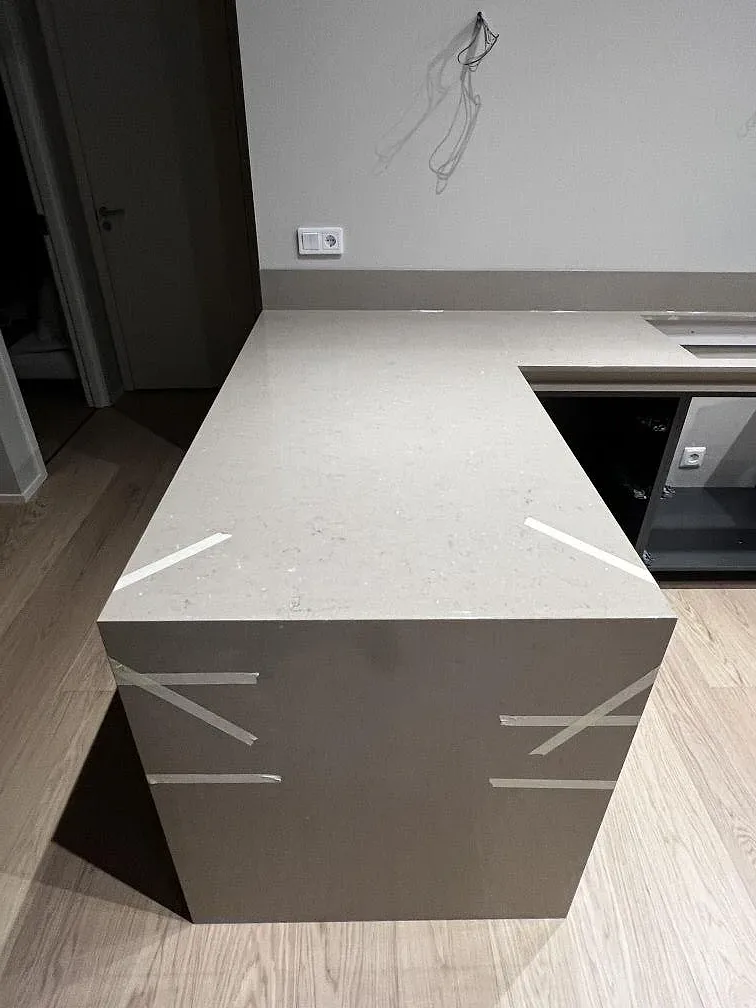 Köksö i Silestone Coral Clay under montering, med maskeringstejp och mörka greppfria stommar i ett kök i Hässleholm.