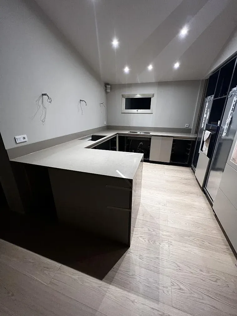 Halvö i polerad Silestone Coral Clay med blond ekparkett och takspottar i ett kök i Hässleholm.