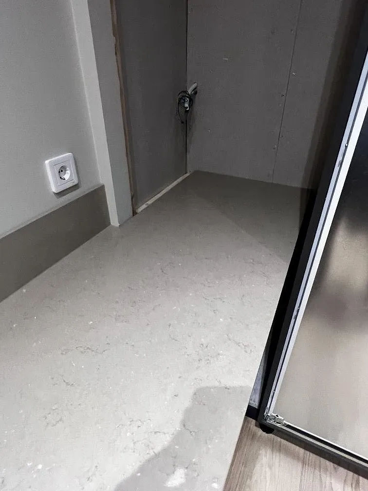 Bänkskiva i Silestone Coral Clay som vinklar runt ett hörn mot oputsad vägg under montering i ett kök i Hässleholm.