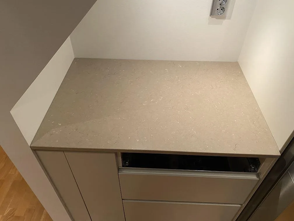 Kort väggbänk i polerad Silestone Coral Clay under sned vägg, monterad i kök i Hässleholm.
