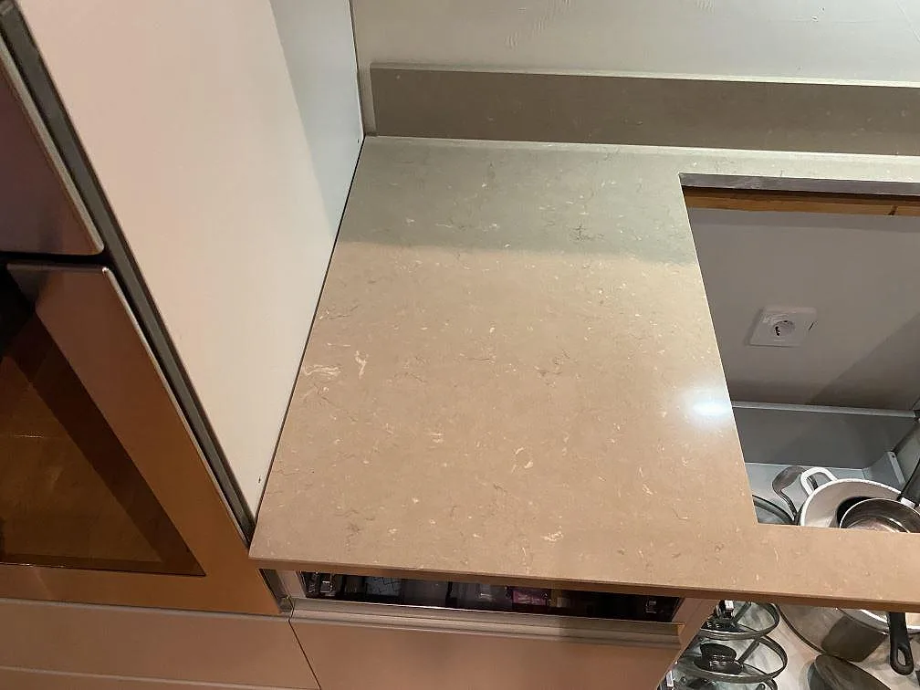 Väggbänk i polerad Silestone Coral Clay med låg stänkkant och rektangulärt urtag i kök i Hässleholm.