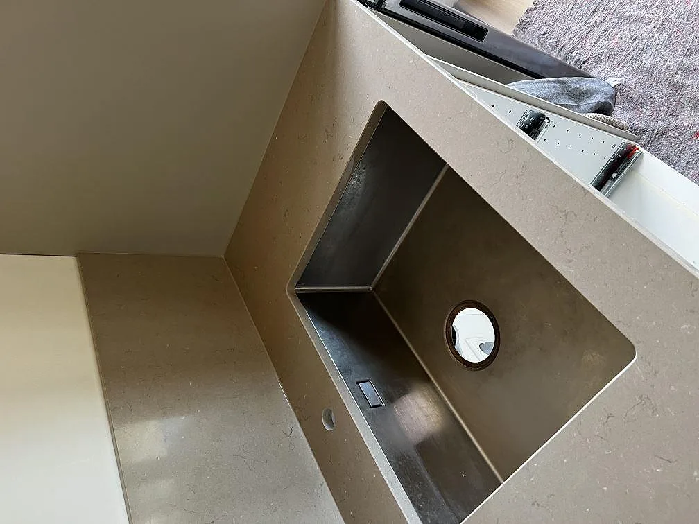 Underlimmad rostfri diskho i en polerad bänkskiva av Silestone Coral Clay i ett kök i Heberg.