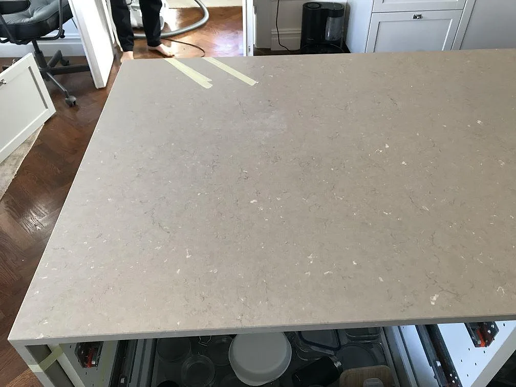 Köksbänkskiva i greige Silestone Coral Clay med infälld induktionshäll och uppvikt stänkskydd, mitt under montering