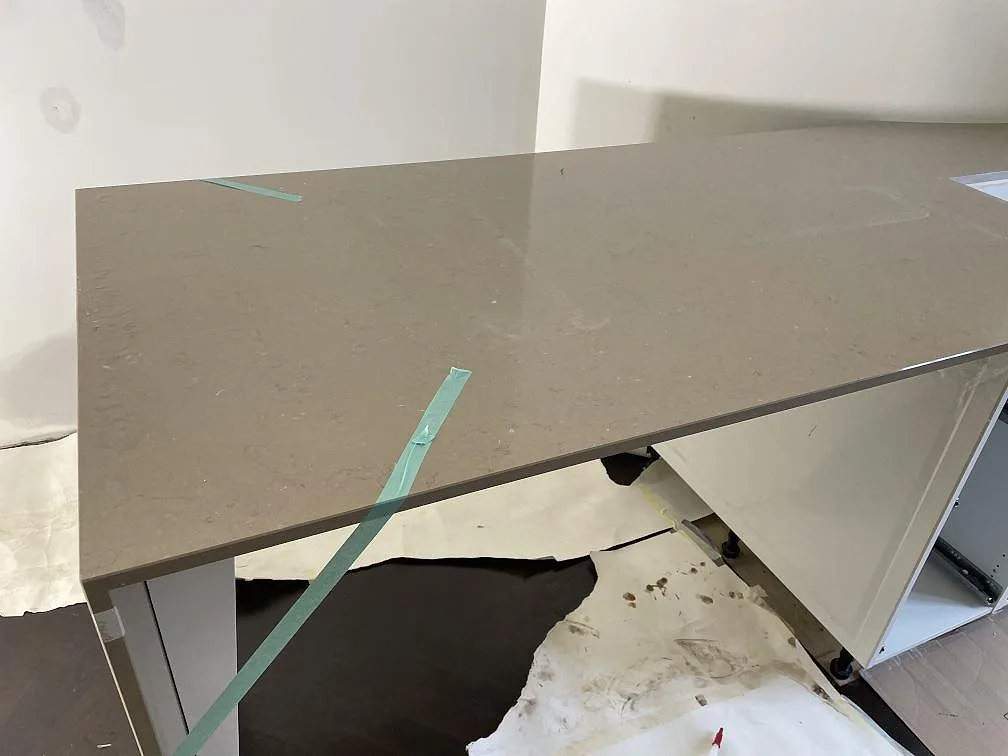 Polerad Silestone Coral Clay bänkskiva över vita stommar under montering i ett mindre arbetsrum i Helsingborg.