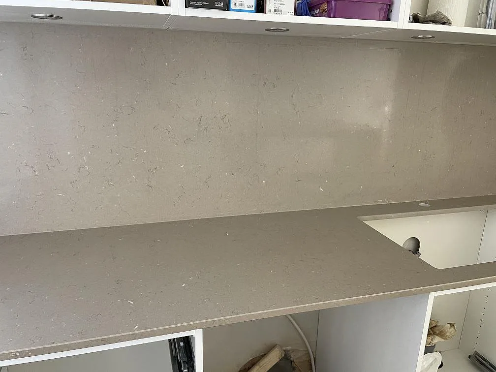 Bänkskiva i polerad Silestone Coral Clay komposit med diskhoöppning och stänkskydd i ett kompakt rum i Helsingborg.