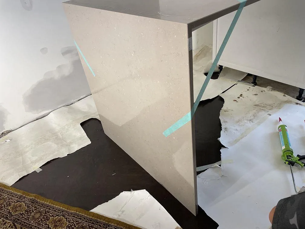 Installerad Silestone Coral Clay komposit med vertikal sidoyta och tejpmarkering under pågående montering i Helsingborg.