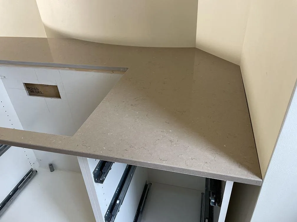 Sidovy av polerad Silestone Coral Clay komposit med tjock framkant och monteringsskydd på golvet i Helsingborg.