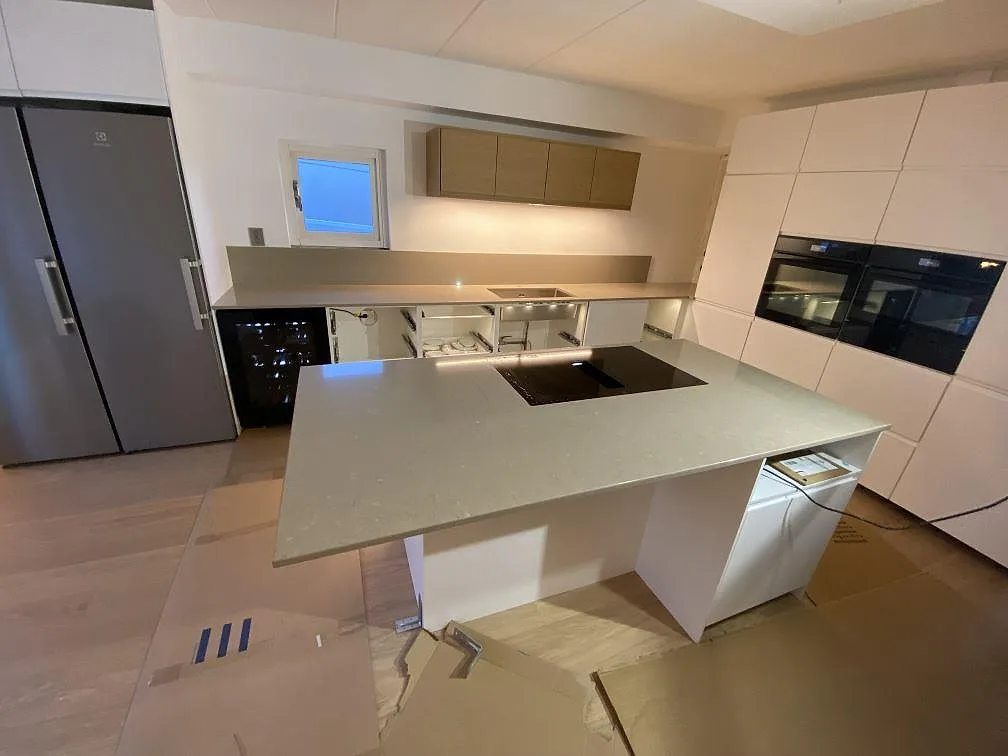 Köksbänkskiva och köksö i polerad Silestone Coral Clay, kvartskomposit, med häll och låg stänkkant i ett kök under montering i Helsingborg.