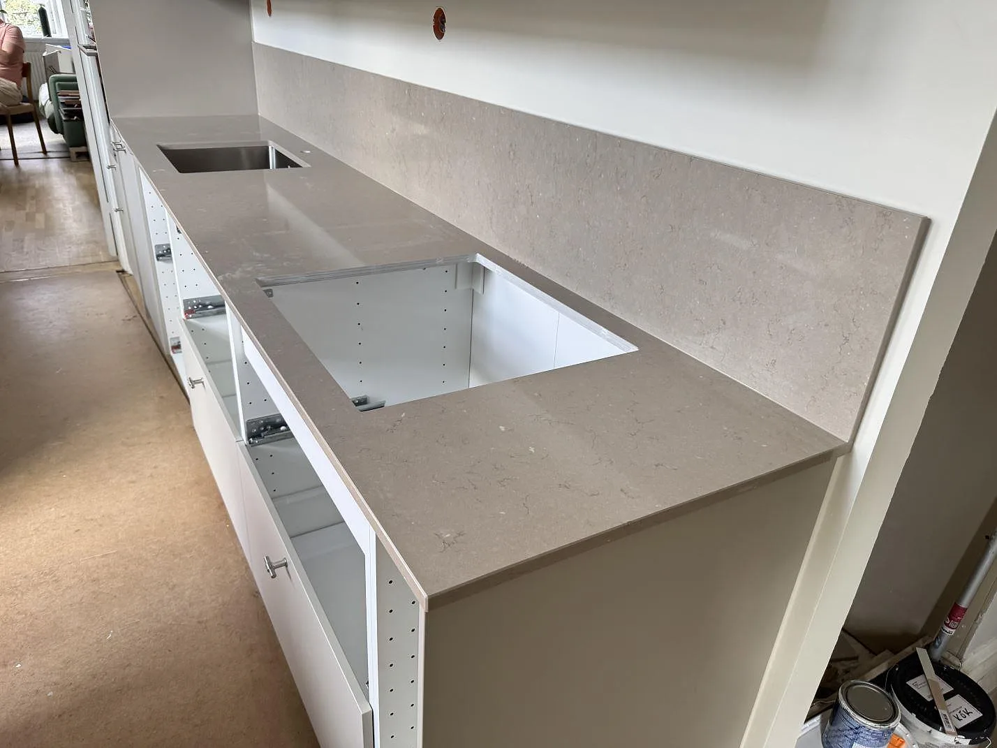 Köksbänkskiva i polerad Silestone Coral Clay, kvartskomposit, med stänkskydd och hällurtag under montering i Helsingborg.