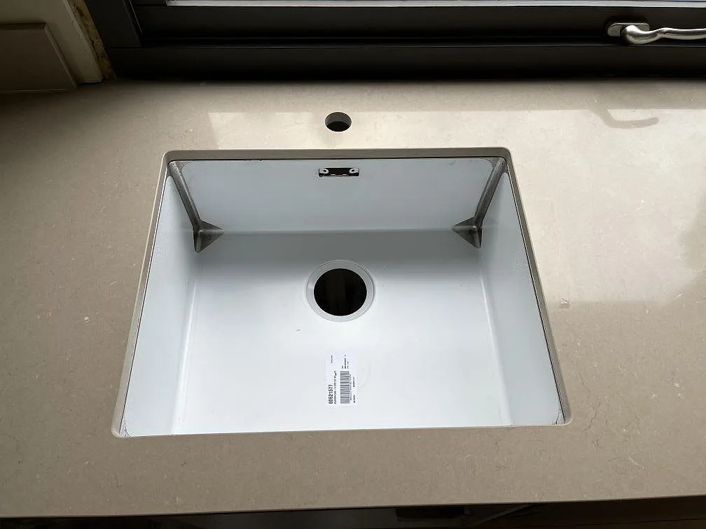 Underlimmad vit diskho med kranhål i en köksbänkskiva av Silestone Coral Clay i Hestra.