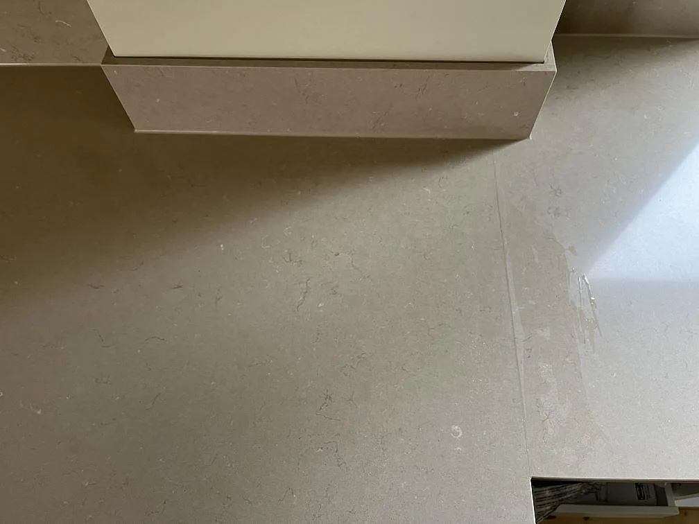 Köksbänkskiva i greige Silestone Coral Clay med uppvikt stänkkant mot köksstomme och fönster i ett kök i Hestra.