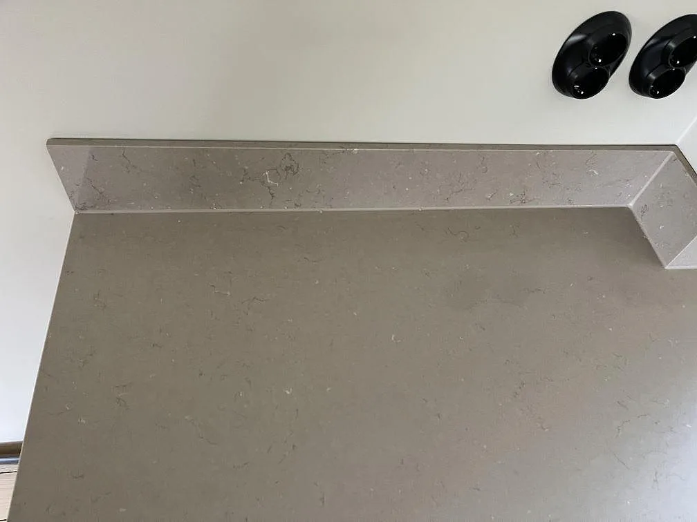 Polerad köksbänkskiva i Silestone Coral Clay med uppvikt stänkkant och eluttag på väggen i ett kök i Hestra.
