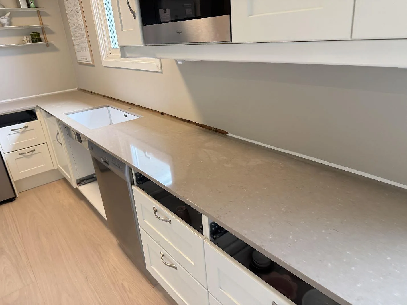 Polerad Silestone Coral Clay som lång köksbänkskiva med synlig diskhoöppning och vit köksinredning i Hisings Backa.