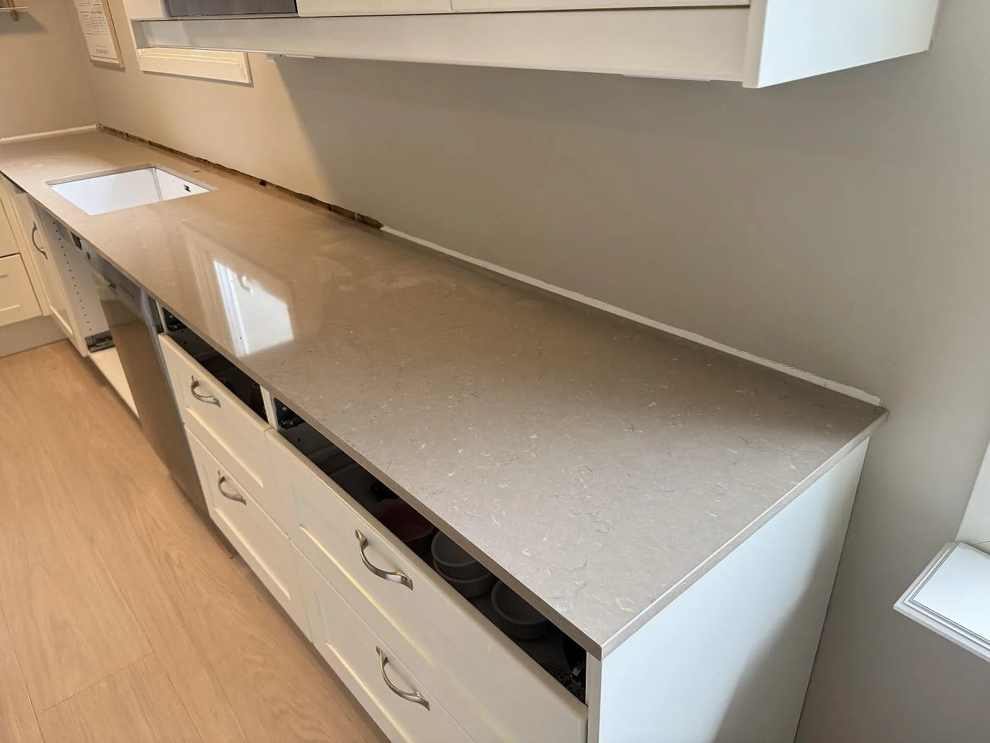 Köksbänkskiva i Silestone Coral Clay, polerad kvartskomposit, längs en vit köksrad i Hisings Backa.