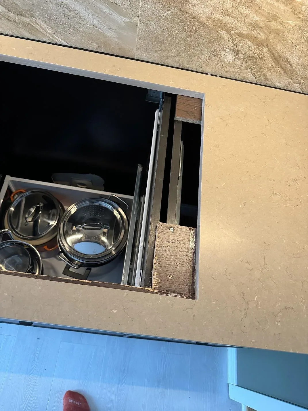 Närbild av hällurtag i Silestone Coral Clay, matt greige komposit, med öppna kökslådor under montering i Höganäs.