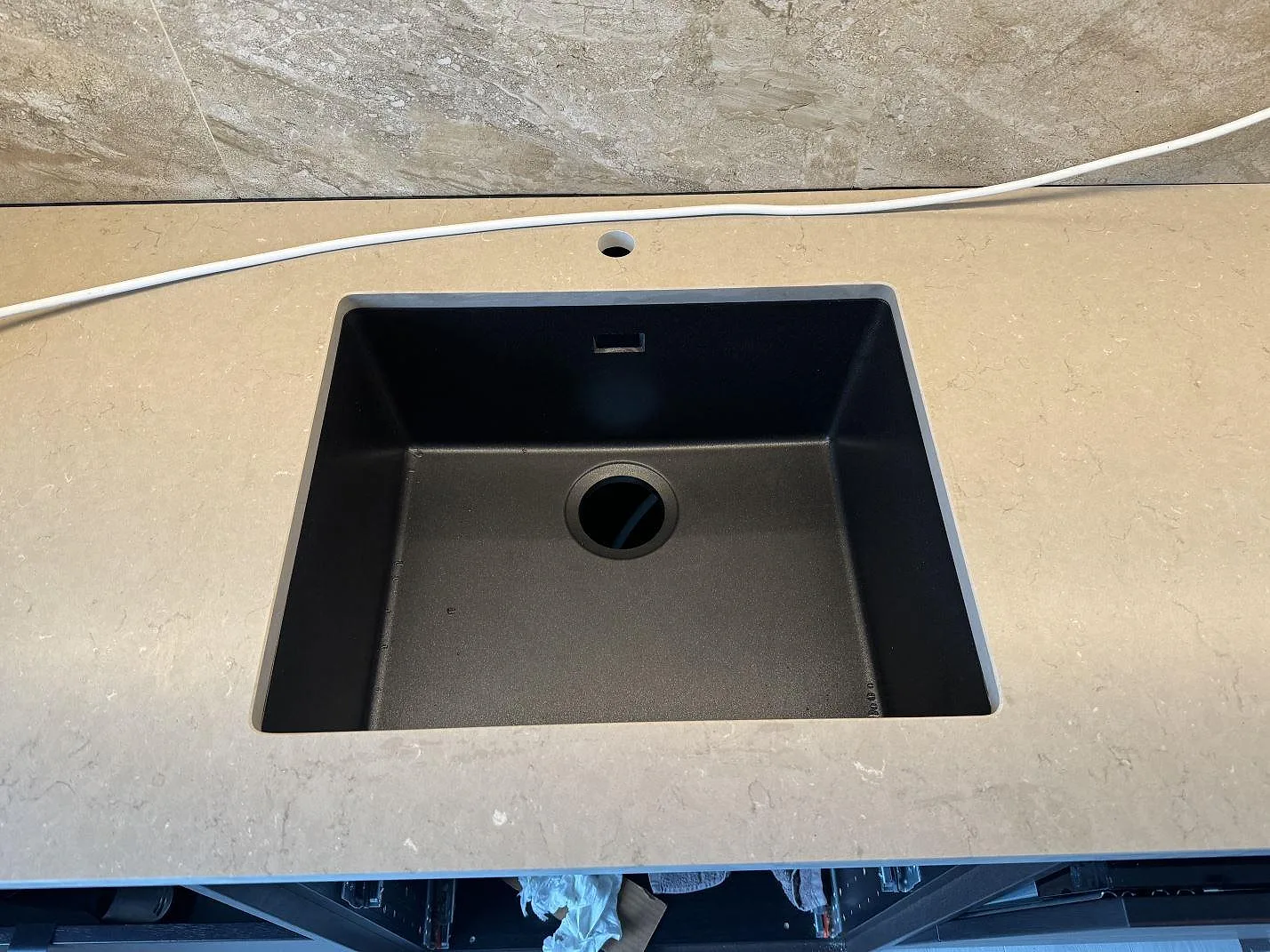Köksbänkskiva i Silestone Coral Clay, Mocka, med svart underlimmad diskho och kranhål framför marmorerat kakel i Höganäs.