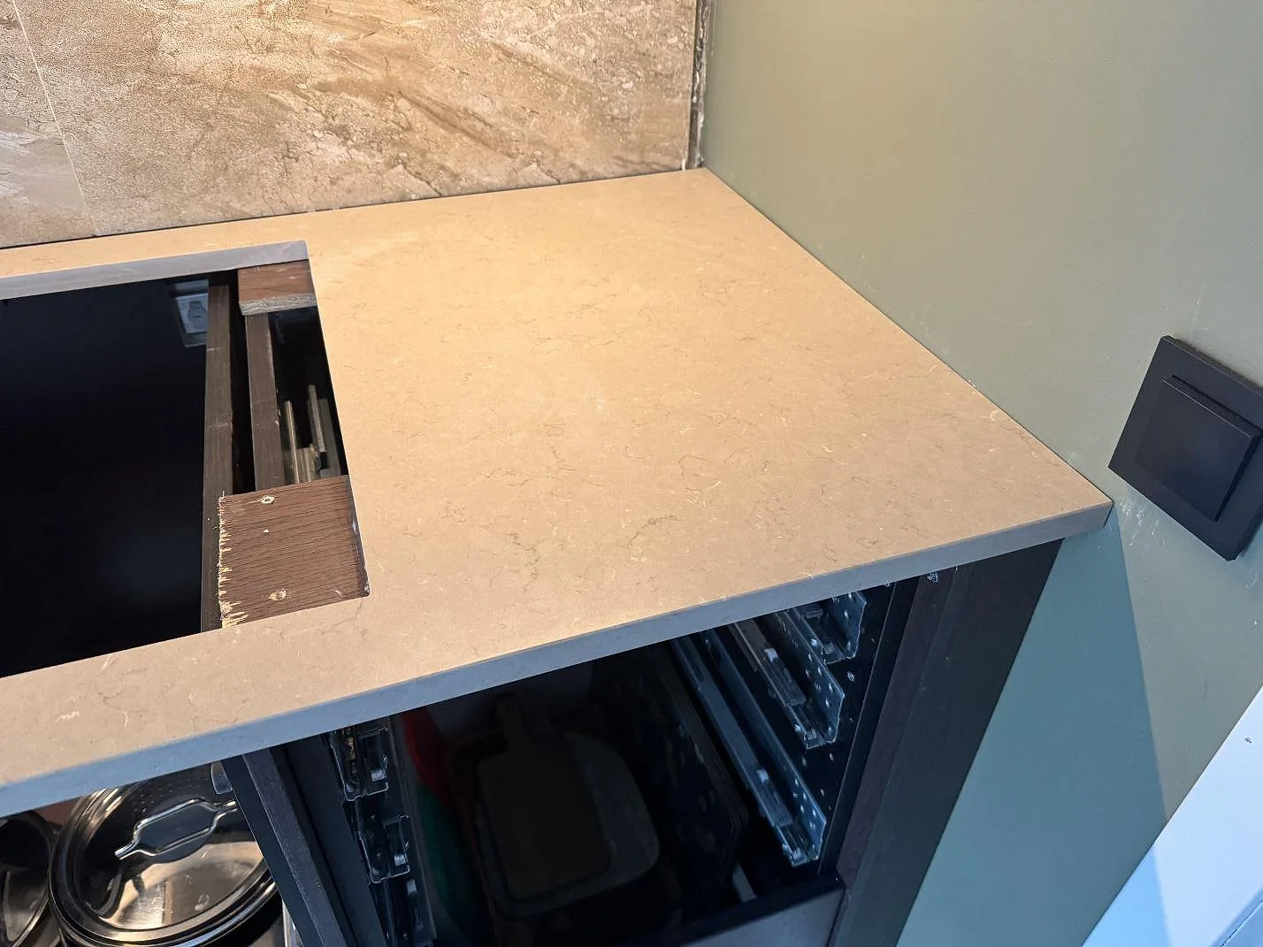 Hörn av bänkskiva i Silestone Coral Clay, Mocka, med hällurtag och marmorerat kakel i ett kök i Höganäs.