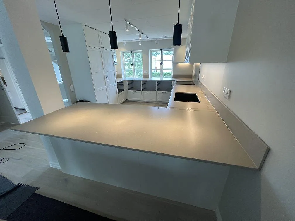 Köksbänkskiva i Silestone Coral Clay, matt Mocka-finish, med halvö, svart häll och diskho i ett kök i Höllviken.