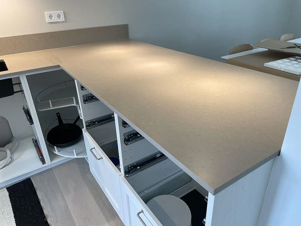 Halvö i Silestone Coral Clay med matt gråbeige yta över vita köksstommar under montering i Höllviken.