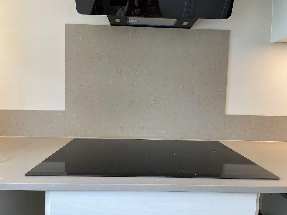 Silestone Coral Clay som köksbänkskiva och stänkskydd bakom svart induktionshäll i Höllviken.