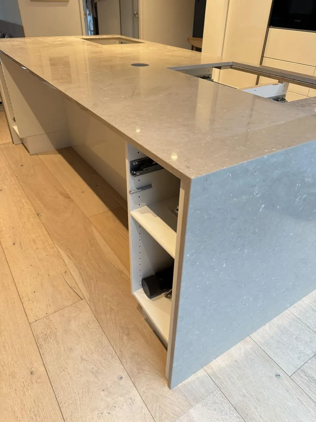 Sidovy av köksö med neddragen stensida i Silestone Coral Clay, polerad kvartskomposit, under montering i Höllviken.