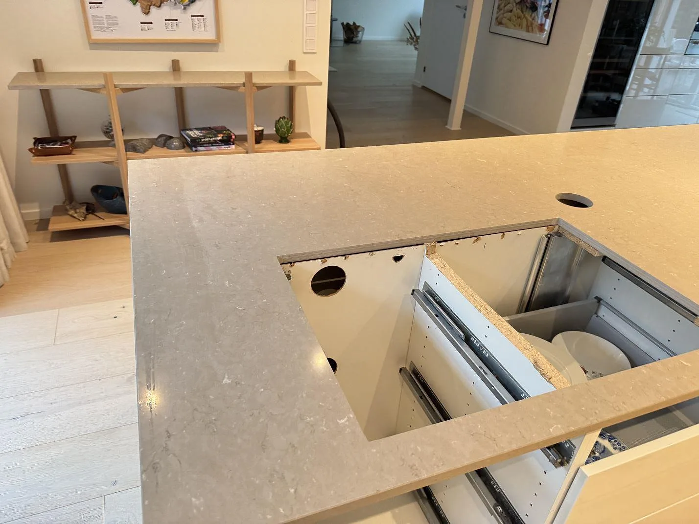 Vinkelvy över köksbänkskiva i polerad Silestone Coral Clay, 20 mm, med öppna köksstommar och separat skiva på träinredning i Höllviken.