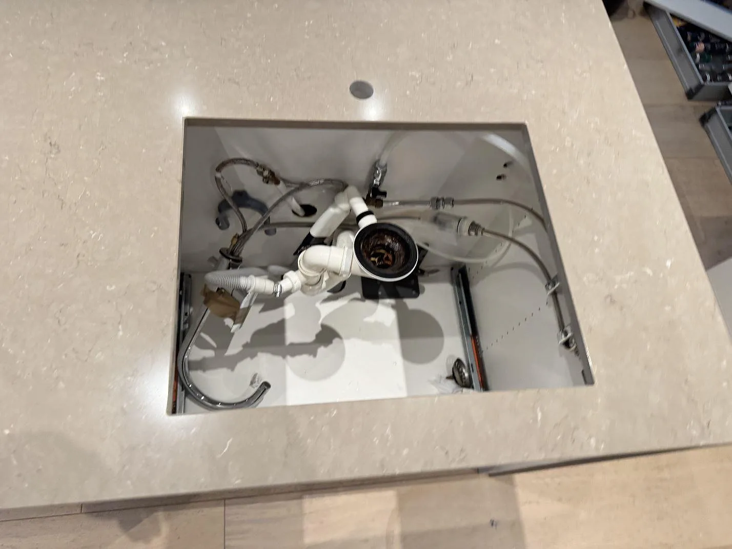 Närbild av rektangulärt urtag i polerad Silestone Coral Clay ovanför synlig vatteninstallation i ett kök i Höllviken.
