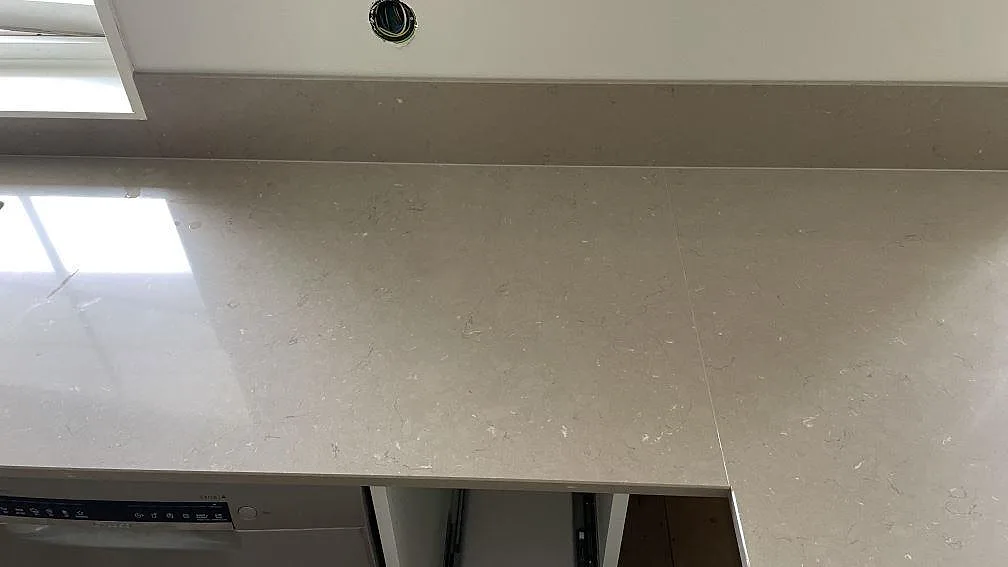 Närbild på polerad Silestone Coral Clay med diskret ljus ådring, fönsterreflex och låg stänkkant i Höör.
