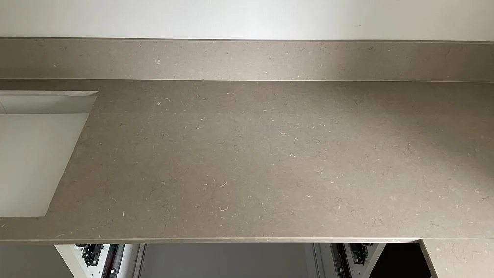 Rak bänkrad i polerad Silestone Coral Clay med låg stänkkant och öppen köksstomme under montering i Höör.