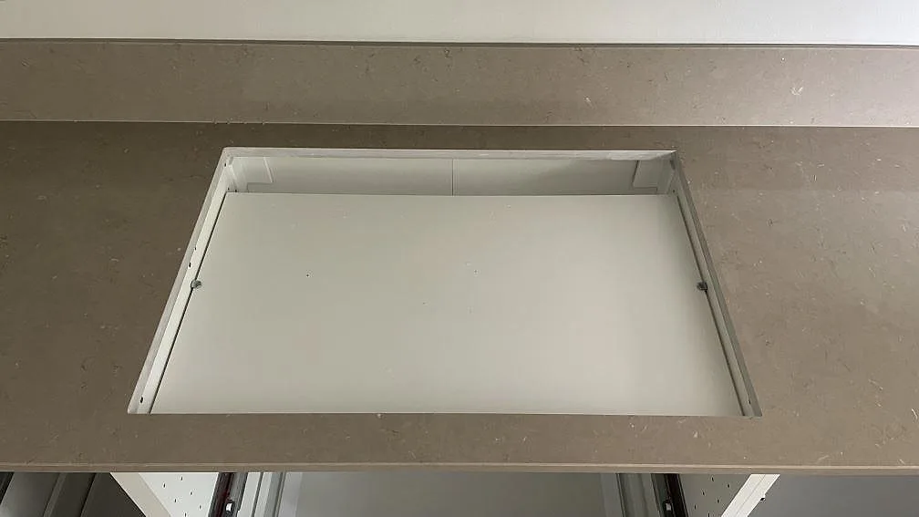 Rektangulär hällöppning i polerad Silestone Coral Clay med låg stänkkant bakom i köket i Höör.