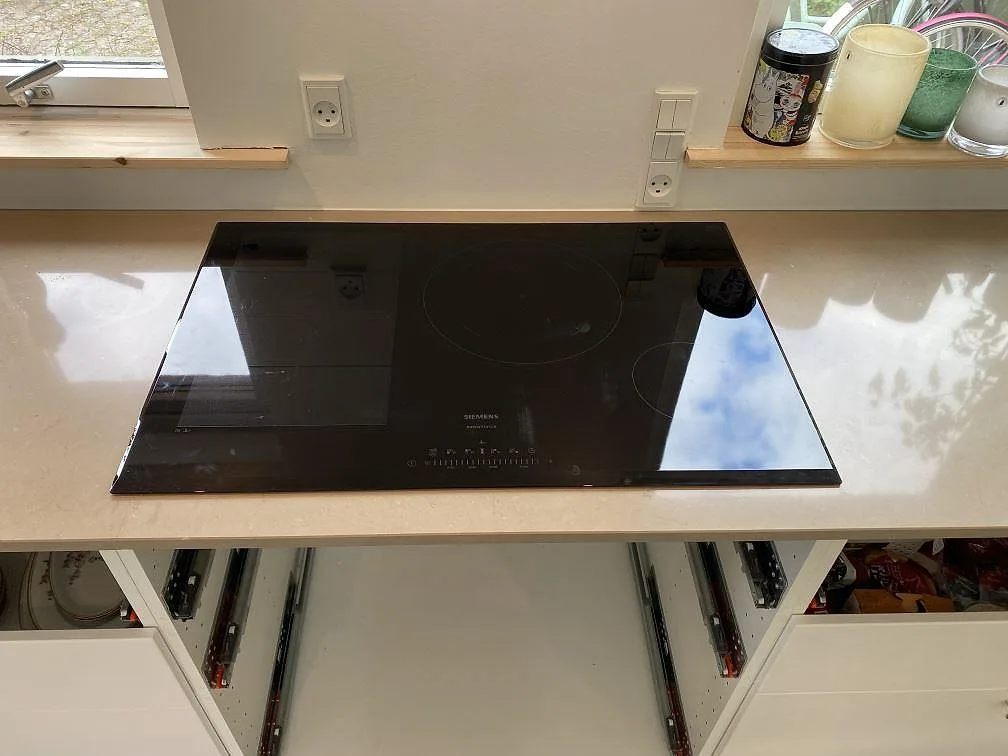 Siemens induktionshäll infälld i en köksbänkskiva av Silestone Coral Clay, polerad komposit, längs fönsterväggen i ett kök i Hørsholm.