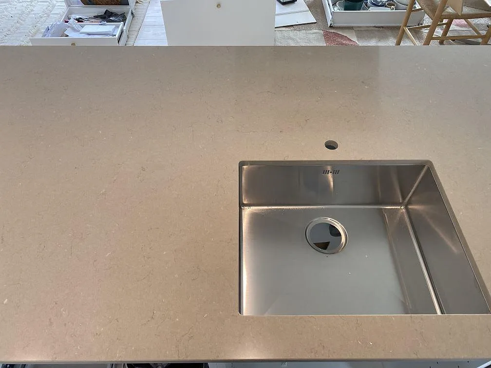 Topbild på den underlimmade rostfria diskhon i köksön av Silestone Coral Clay, polerad kvartskomposit, i ett kök i Hørsholm.