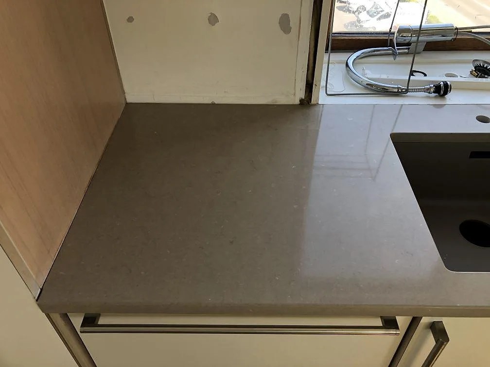 Polerad köksbänkskiva i Silestone Coral Clay med underlimmad diskho och köksblandare vid fönstret i ett kök i Holbæk.