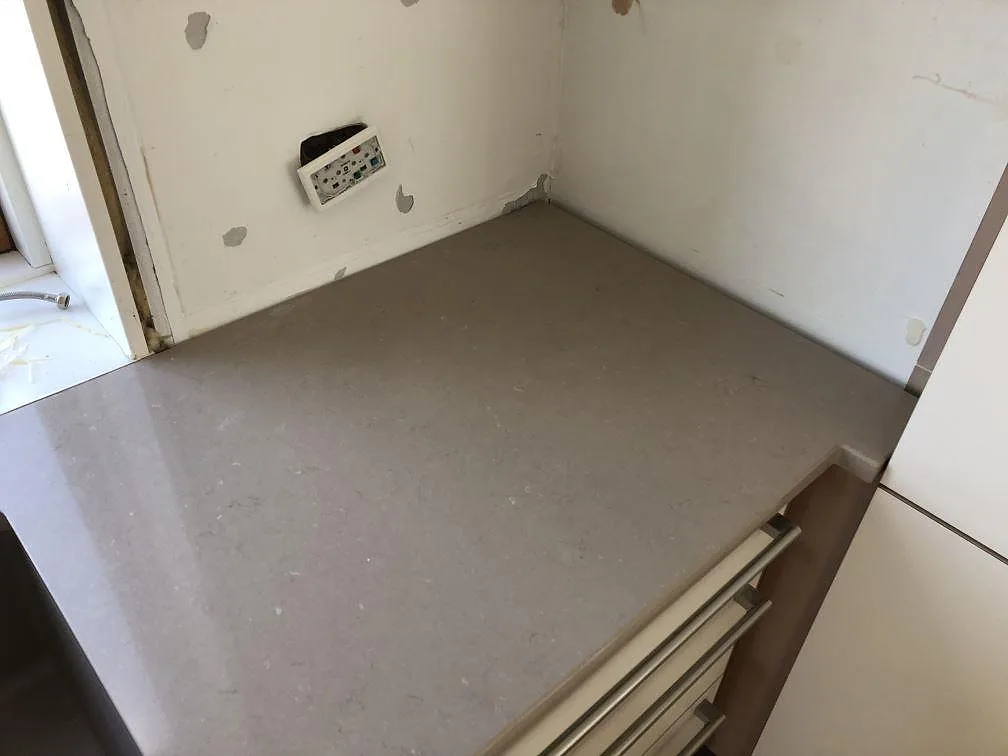 Bänkskiva i Silestone Coral Clay i hörnläge under montering, greige komposit med polerad yta i ett kök i Holbæk.