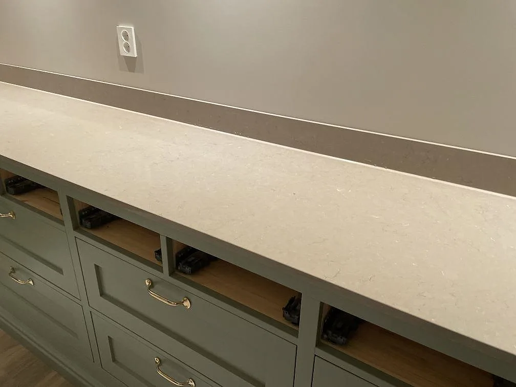 Rak del av köksbänkskiva i polerad Silestone Coral Clay med lågt stänkskydd och mässingshandtag i Holsbybrunn.