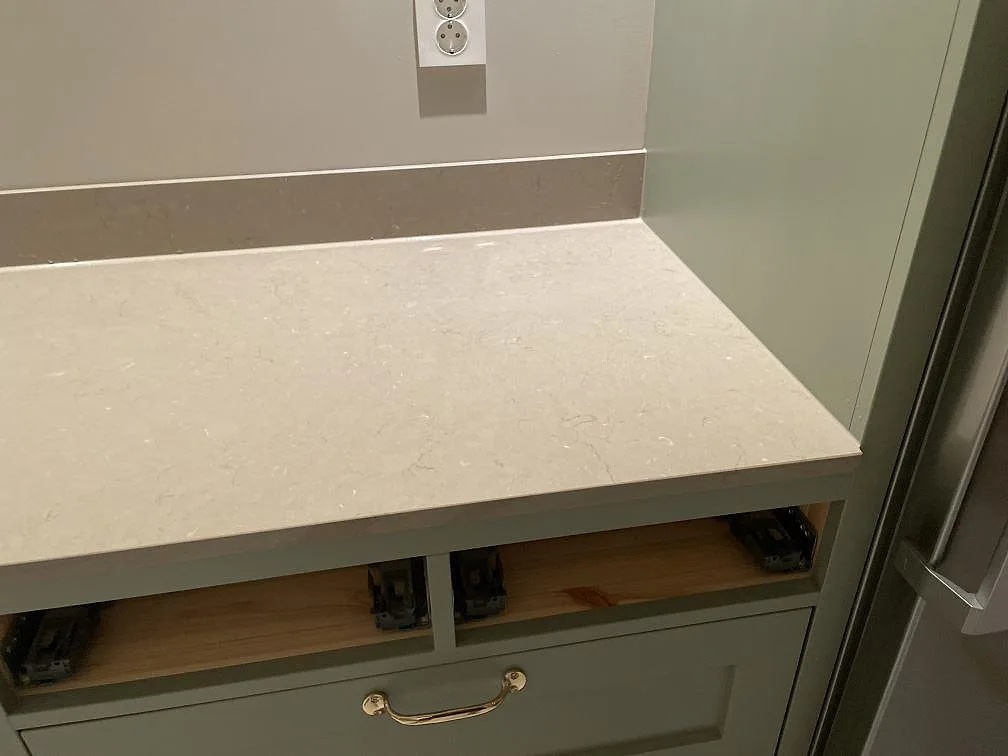 Närbild på polerad Silestone Coral Clay komposit som bänkskiva med 12 mm stänkskydd över salviagröna köksskåp i Holsbybrunn.