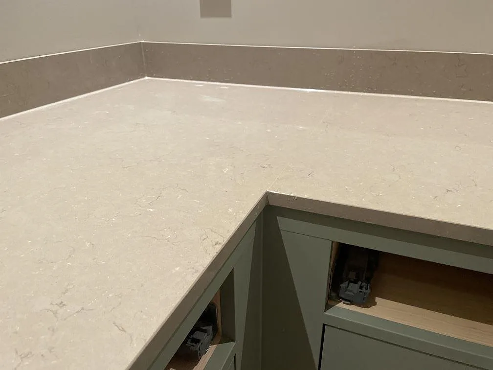 Hörn i L-formad köksbänkskiva av Silestone Coral Clay med polerad yta och uppvikt stänkkant i Holsbybrunn.