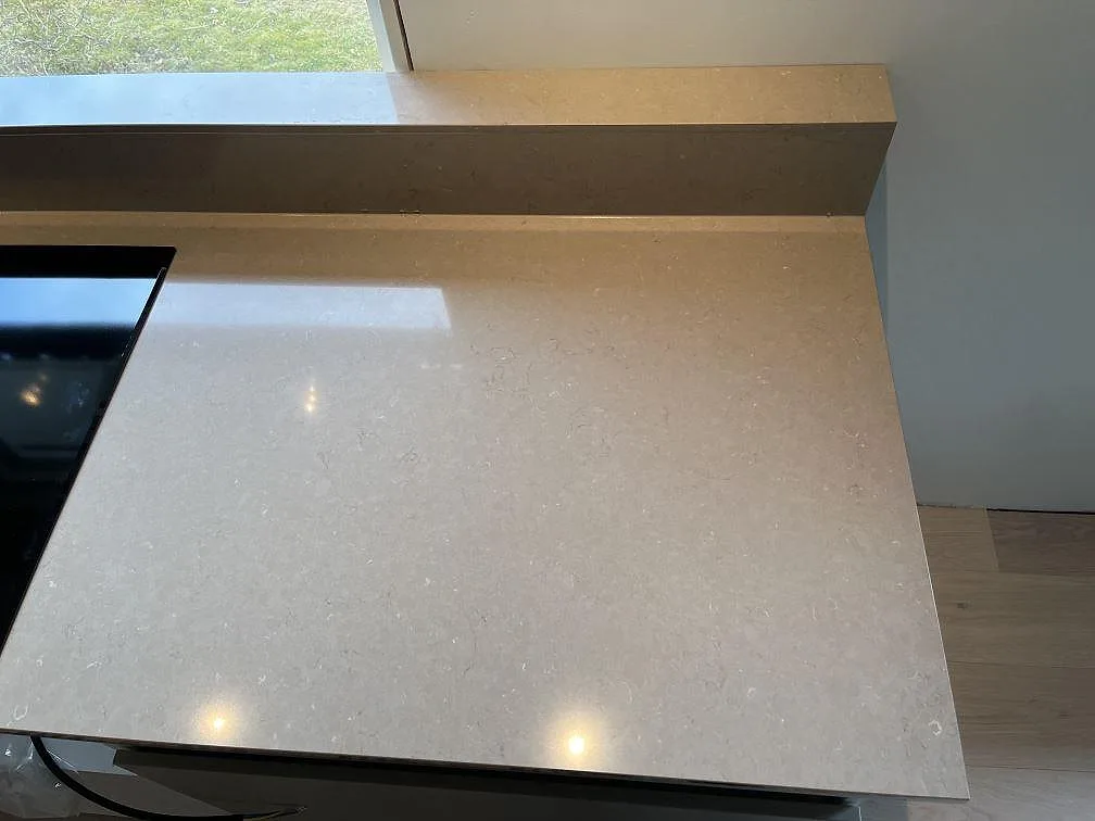 Infälld svart induktionshäll med integrerad fläkt i polerad Silestone Coral Clay köksbänkskiva i ett kök i Ingelstad.