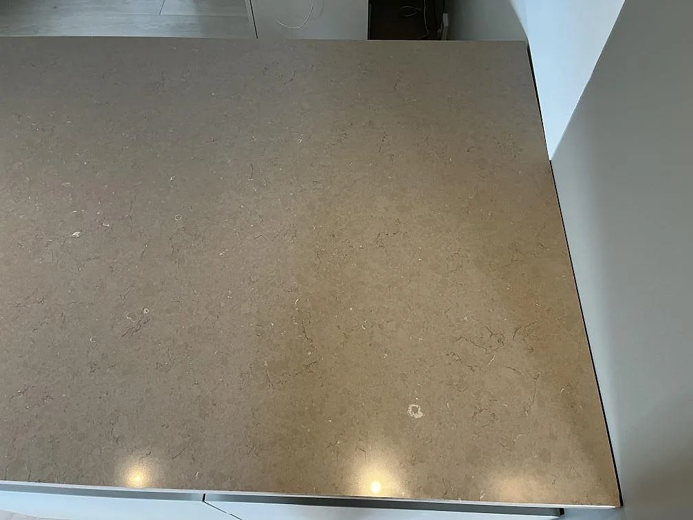 Polerad Silestone Coral Clay köksbänkskiva med kraftig kantprofil och svart häll i ett kök i Ingelstad.