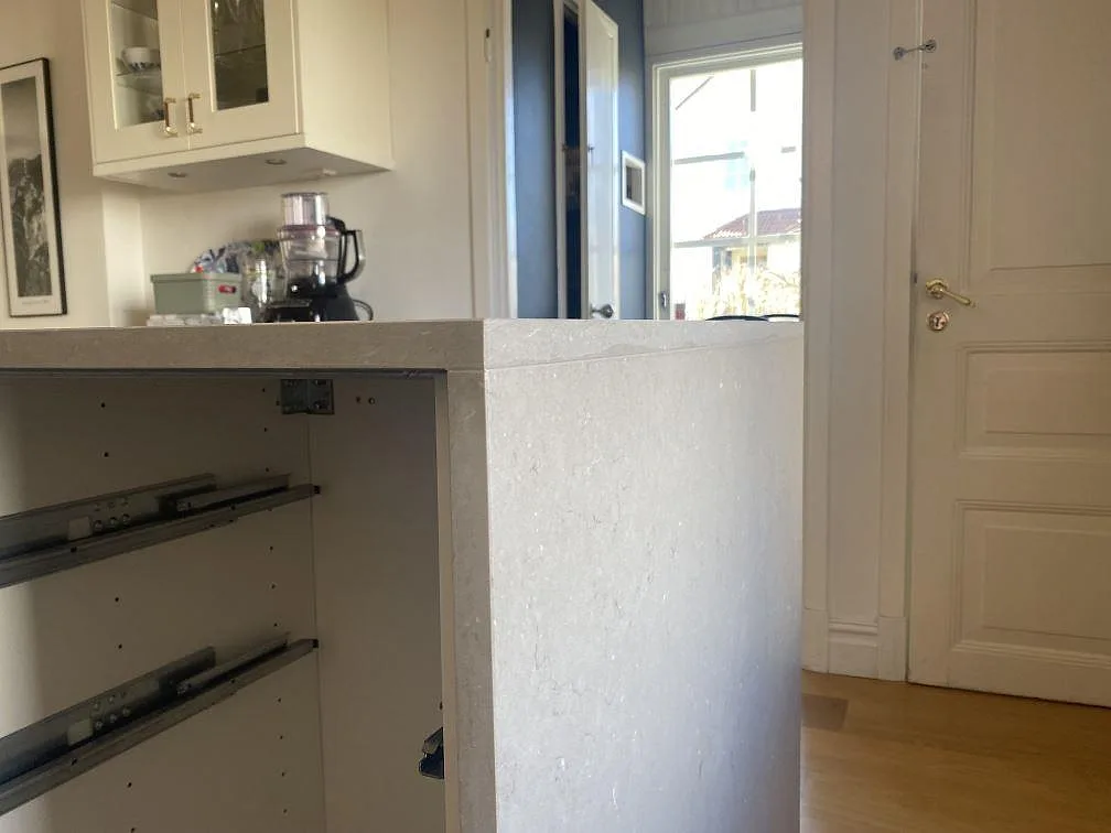 Närbild av köksöns lodräta stenpanel och bänkskivans kant i matt Silestone Coral Clay komposit i Jönköping.