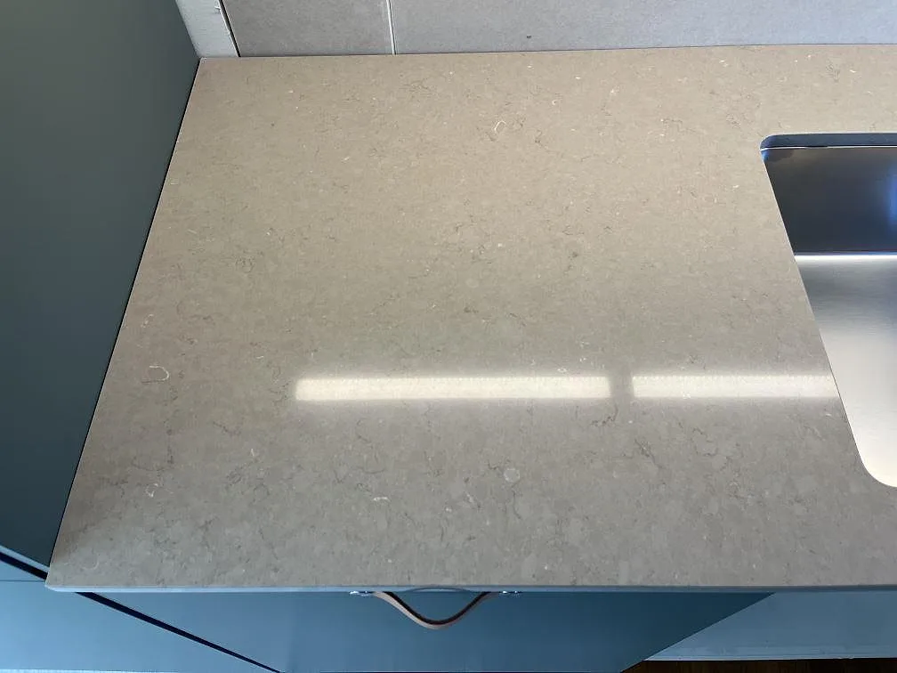 Köksbänkskiva i Silestone Coral Clay med underlimmad rostfri diskho och matt yta mot grön-grå kökslucka, Kållered.