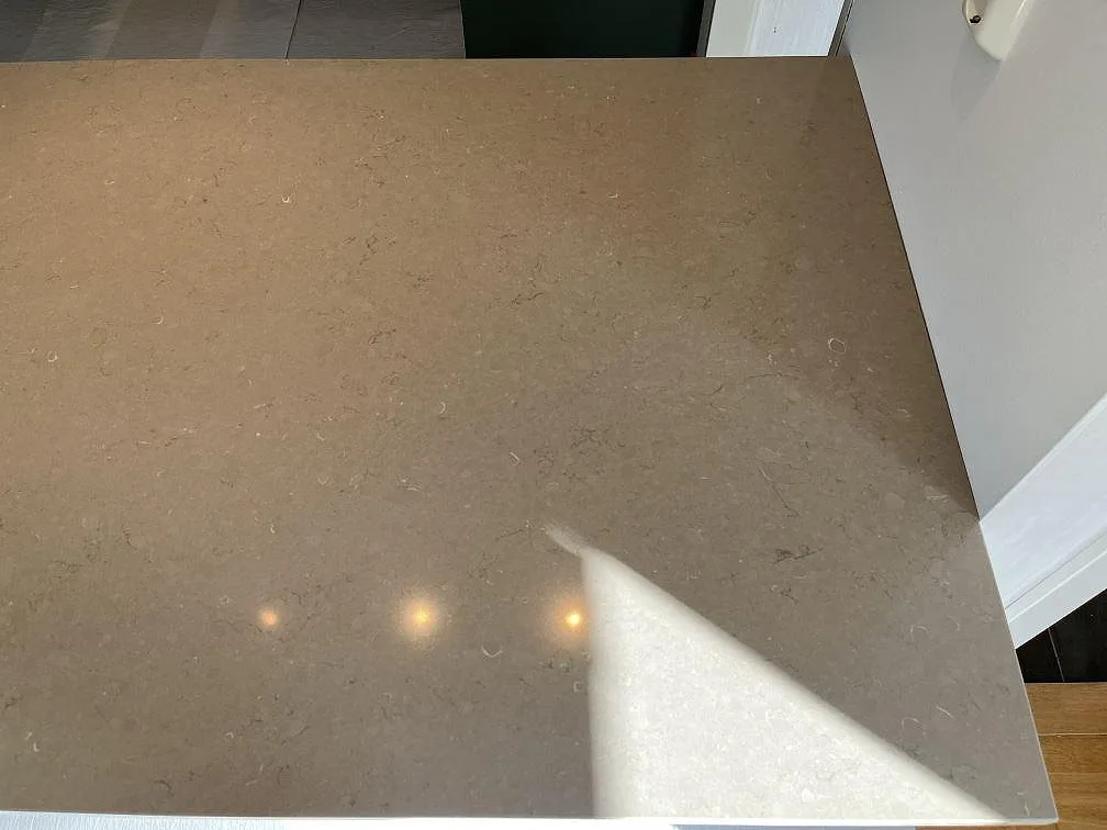Köksbänkskiva i matt Silestone Coral Clay mot grön vägg och trägolv i ett kök i Kållered.
