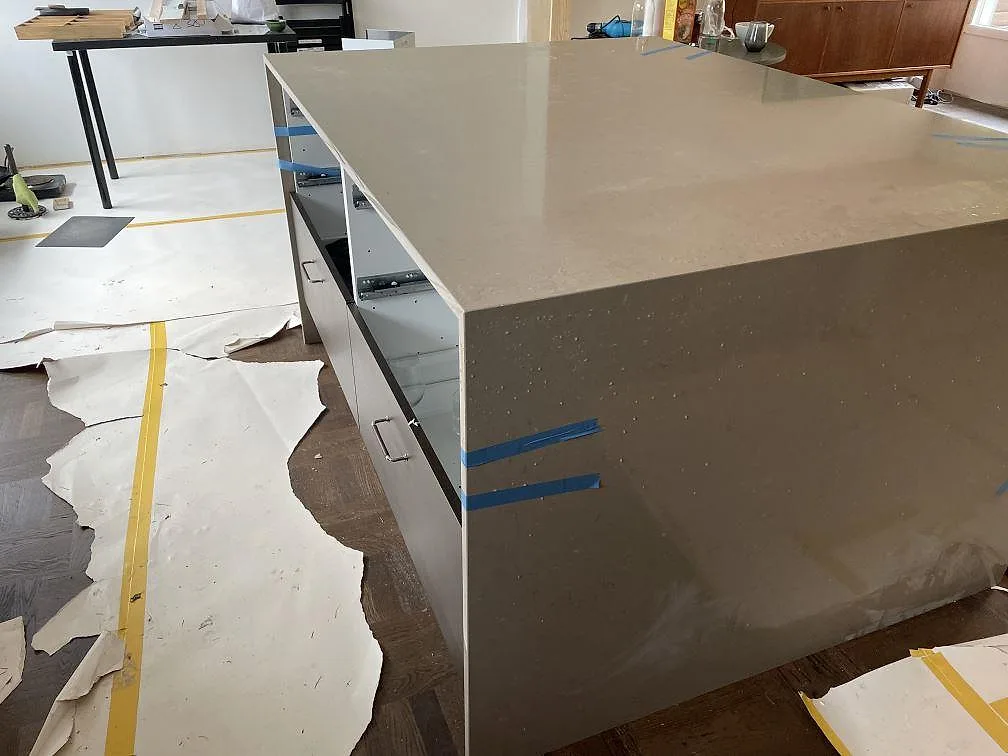 Närbild på stor köksö med topp och sidor i polerad Silestone Coral Clay komposit under montering i Kållered.