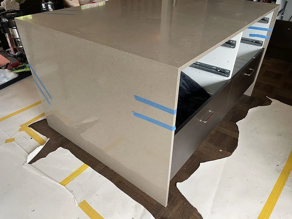 Köksö med vattenfallssidor i polerad Silestone Coral Clay komposit, monterad framför mörka luckor i Kållered.