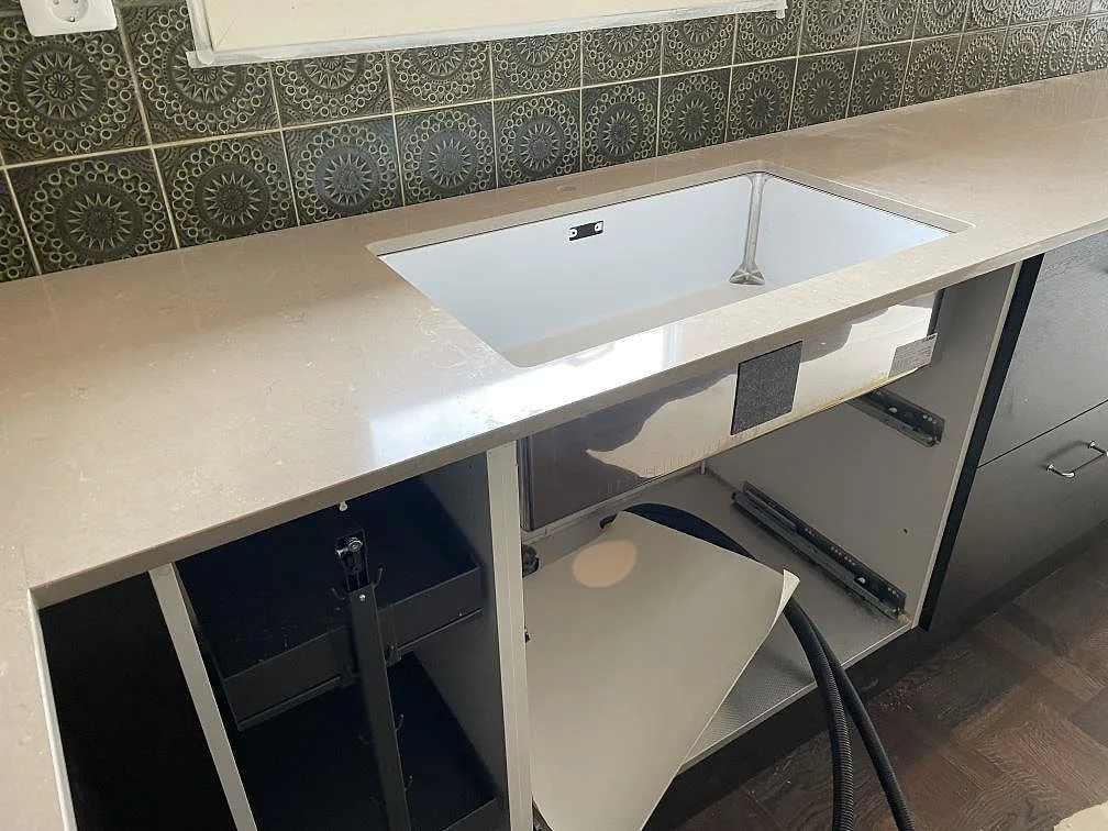 Underlimmad vit diskho i polerad Silestone Coral Clay komposit med grön kakelvägg i ett kök i Kållered.