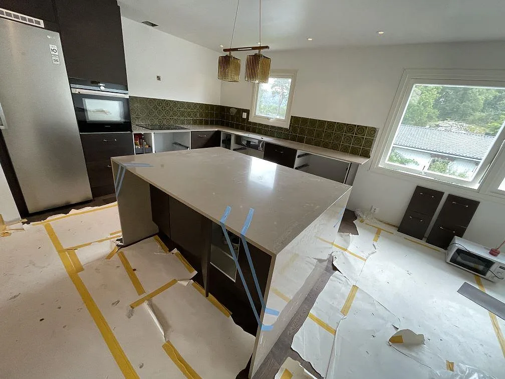 Polerad köksbänkskiva i Silestone Coral Clay komposit med stor köksö, väggbänkar och grönt mönstrat kakel i Kållered.