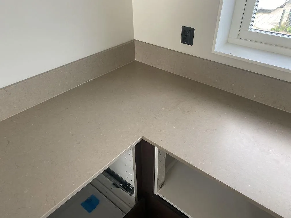 Hörnparti med bänkskiva i matt Silestone Coral Clay komposit och bred fönsterbänk i ett kök i Kalmar.