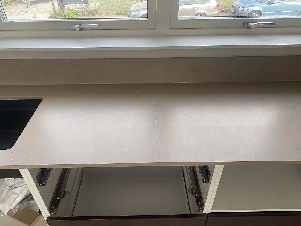 Bänkskiva i Silestone Coral Clay, matt komposit, under fönster med en svart kompositdiskho i kanten i ett kök i Kalmar.
