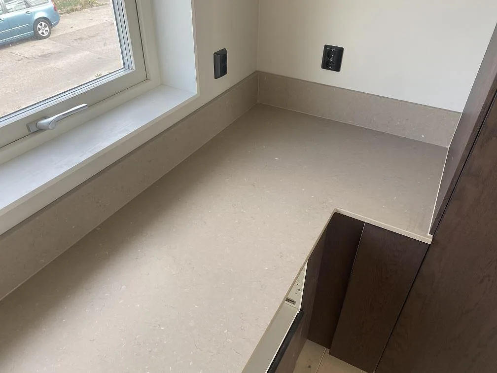 Bänkskiva och fönsterbänk i Silestone Coral Clay, matt greige komposit, längs fönstervägg i ett kök i Kalmar.